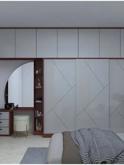 A spacious master bedroom wardrobe with a geometric pattern on the sliding doors. The unit includes an attached dressing table with a mirror, creating a complete vanity solution.