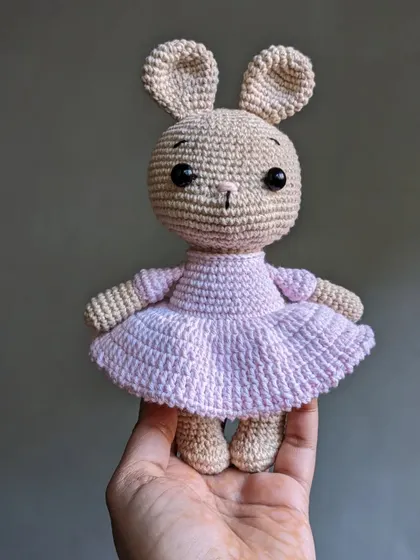 A sweet bunny doll wearing a frilly pink dress, ready for a party.