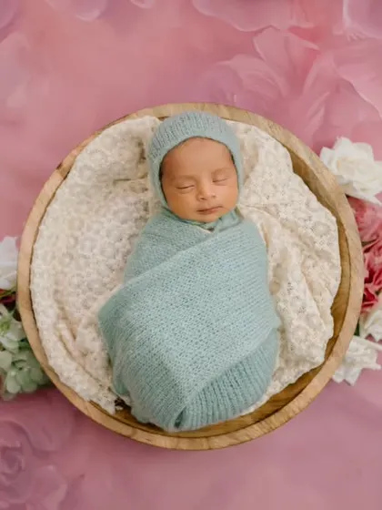 Sleeping peacefully on a bed of pink clouds. This dreamy setup with a soft blue swaddle creates a beautiful, artistic portrait of a newborn.