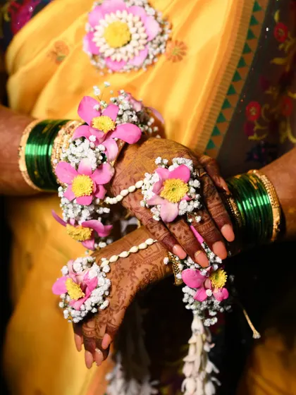 A detailed shot of the bride's hands, adorned with intricate hathphool. The pink and yellow flowers with mogra buds are a classic combination for any Haldi look.