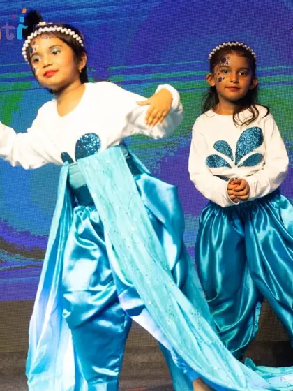 Two girls perform a graceful dance, their blue costumes and flowing sashes evoking the movement of water.