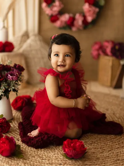 A beautiful baby girl in a red tutu, surrounded by flowers. This setup is perfect for a special milestone like a half-birthday or first birthday.