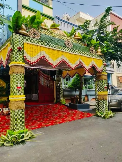 A grand and elegant chapara (entrance arch) for a housewarming or wedding. This structure is made from woven coconut leaves and decorated with flowers and brass kalashas.
