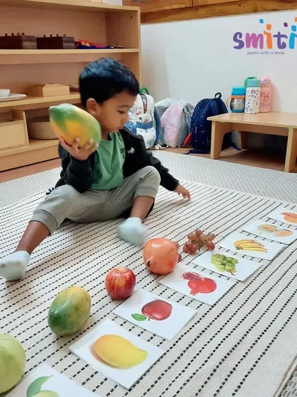 A student carefully places a papaya next to its picture card. This matching game helps solidify his knowledge of different fruits and their names.