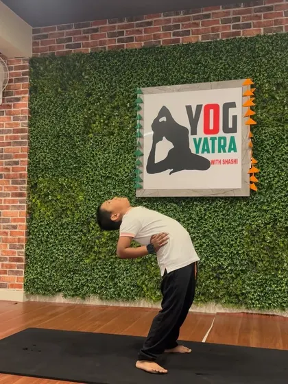 A young student practices a standing backbend, showing great focus and balance.