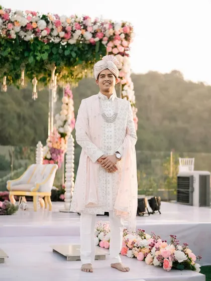 The groom stands proudly at his mandap, looking regal in his pastel sherwani. A moment of calm before the celebrations begin.