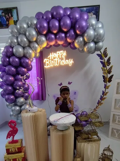 A birthday girl posing with her purple and silver butterfly-themed decoration.
