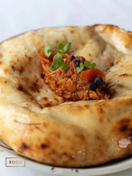 A perfectly baked Smoked Butter Chicken Kulcha, garnished with micro-herbs. It's a complete dish in itself, full of flavour and texture.