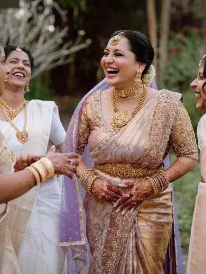 The bride sharing a laugh with her bridesmaids, all dressed in beautiful traditional off-white sarees.