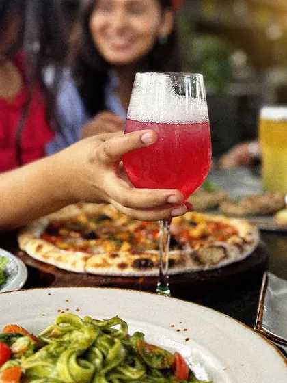 A close-up of a guest enjoying one of our colorful cocktails during a meal with friends.