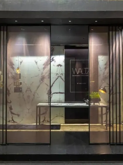 This exhibition for Waltz by JB Glass uses vertical louvers and translucent panels to create a sense of intrigue. The design invites visitors to peek inside, offering glimpses of the products within a sophisticated, layered environment.