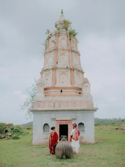 A couple in traditional attire stands before an old temple, creating a timeless pre-wedding photograph.