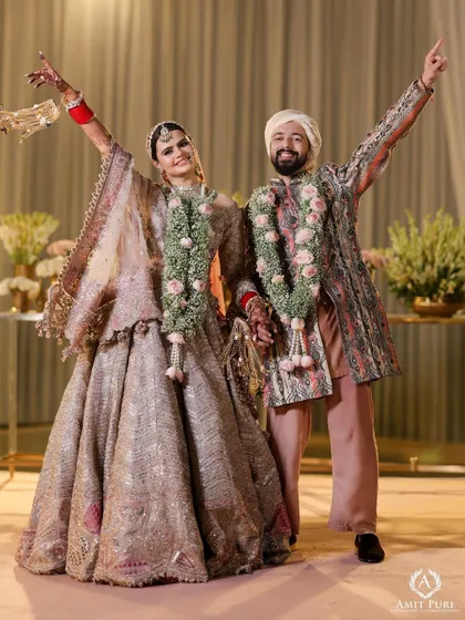 A joyful and energetic portrait of the couple after their Jaimala ceremony. Their hands raised in celebration, this shot captures the pure happiness and excitement of the moment.