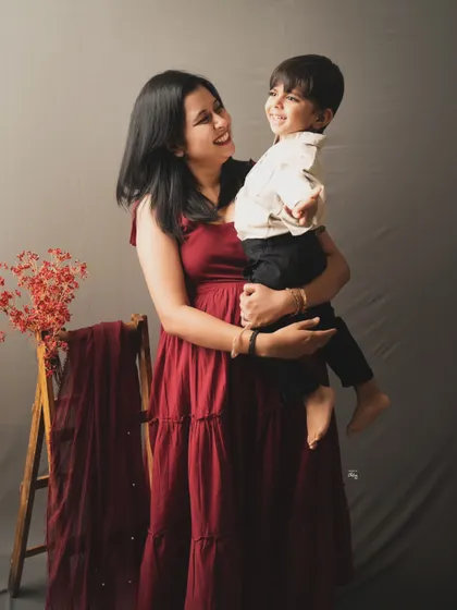 A mother and son sharing a sweet, candid moment. The simple studio setup with a pop of color from the draped fabric adds a lovely artistic touch.