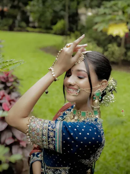 A playful and happy shot of a bride in a gorgeous blue lehenga. The makeup is fresh and dewy, with a floral bun that adds a touch of whimsy for a pre wedding event.