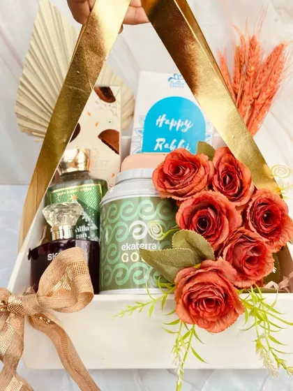 A gorgeous triangular basket hamper designed for a 'Bhaiya-Bhabhi' duo. It includes premium perfumes and treats, adorned with flowers for an elegant touch.