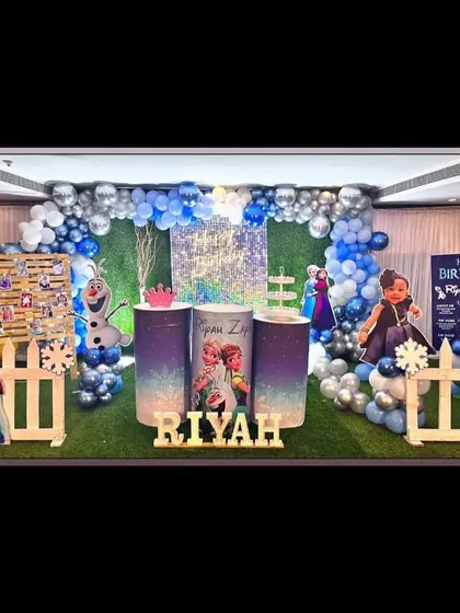 A Frozen-themed setup with a green turf floor, a white picket fence, and an icy blue and silver color scheme.