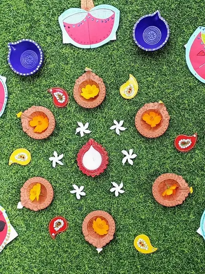 A beautiful arrangement of handmade and real diyas on the grass, creating a festive rangoli.