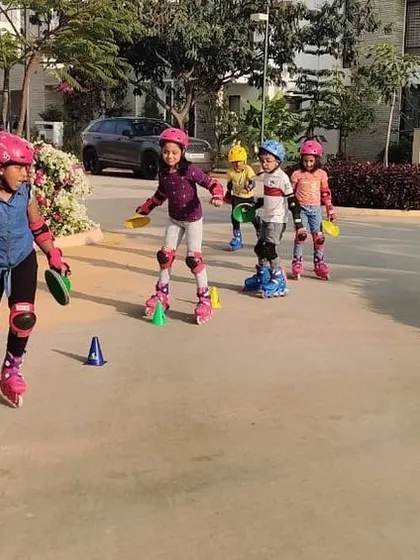 A line of determined young skaters practices their moves in a beautiful outdoor setting. We believe skating is a fantastic activity that gets kids outside and active.
