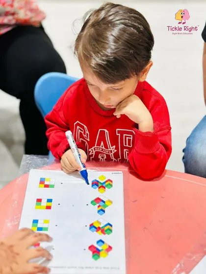 This little boy is deep in concentration as he completes a colorful block pattern puzzle. This activity sharpens his visual discrimination, problem-solving, and logical reasoning skills.