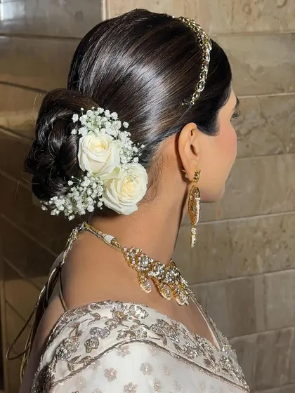 A side view of the messy bun with a fresh white rose, showing how it beautifully complements the bride's white and gold lehenga.
