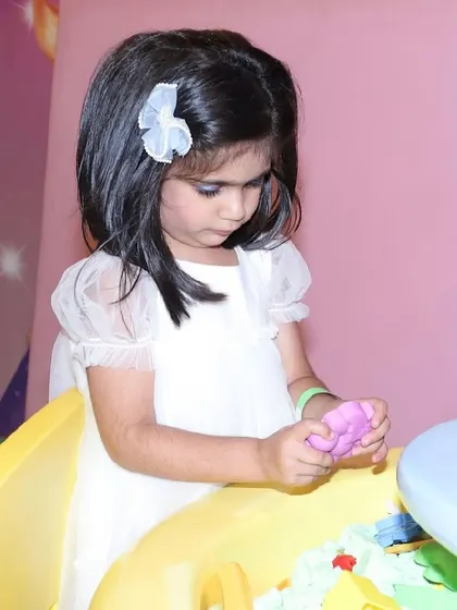 A young girl plays with kinetic sand at a table.