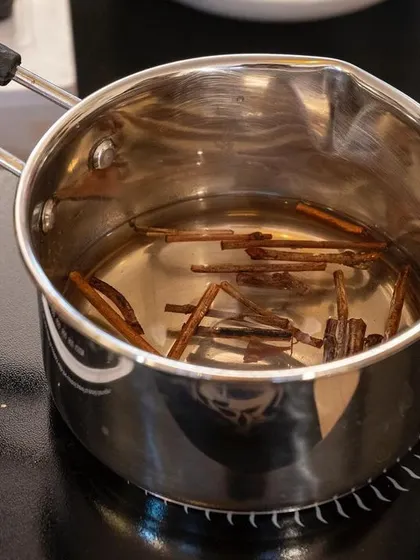 Sappanwood steeping in water on an induction cooktop. This is a key step in the ink extraction process, where we gently heat the botanicals to release their vibrant natural colors.