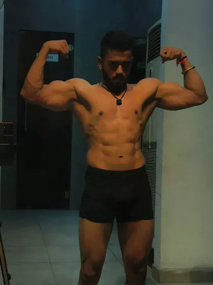 Strong core, strong life. This bicep pose shows a complete physique with a tight midsection and muscular arms.