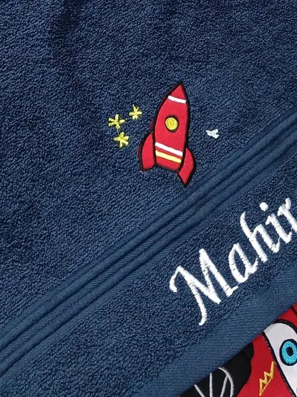 A custom blue towel with a rocket ship embroidery and the name 'Mahir'.