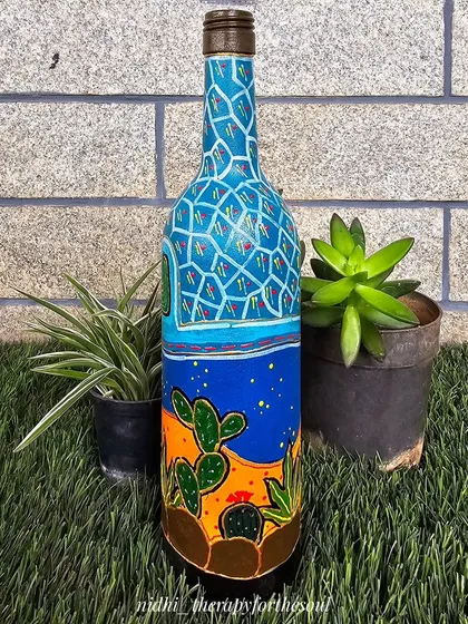 A bottle painted with a desert theme, featuring cacti under a starry night sky and a mosaic-patterned top. This piece is a fun experiment with landscape painting on a curved surface.