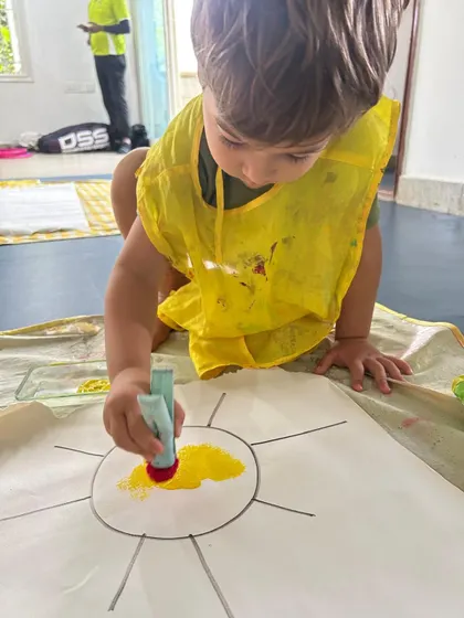 Wearing a protective smock, this boy is engrossed in his sun painting. I ensure children feel comfortable to get a little messy, as it's a natural part of the creative process.