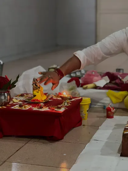 A hand makes an offering to a small deity during a puja ceremony. These rituals, while rooted in tradition, are a part of the vast science of spirituality that helps focus the mind and heart.