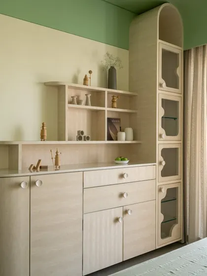 A bedroom in Soft Serve where color blocking in shades of green wraps the walls and ceiling. The furniture is clad in a light Movingue veneer, creating a sense of sculptural quietude.