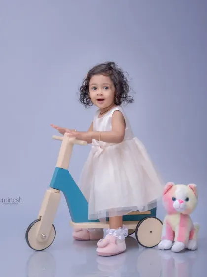 An expressive portrait of a little girl on her toy scooter. Her wide-eyed look and slight smile create an engaging and memorable image.