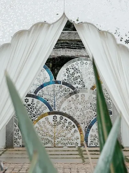 Another perspective of the Thikri entrance, framed by lush greenery. The contrast between the natural elements and the crafted mosaic highlights the beauty of both.