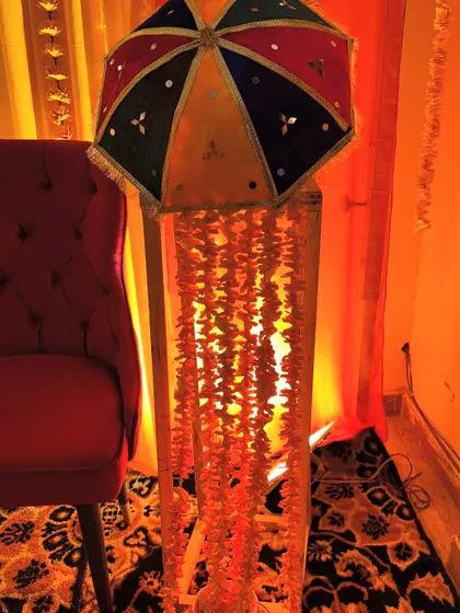 A decorative element for a Haldi setup, featuring a colorful Rajasthani umbrella with hanging marigold strings. This adds a traditional and vibrant touch to the decor.