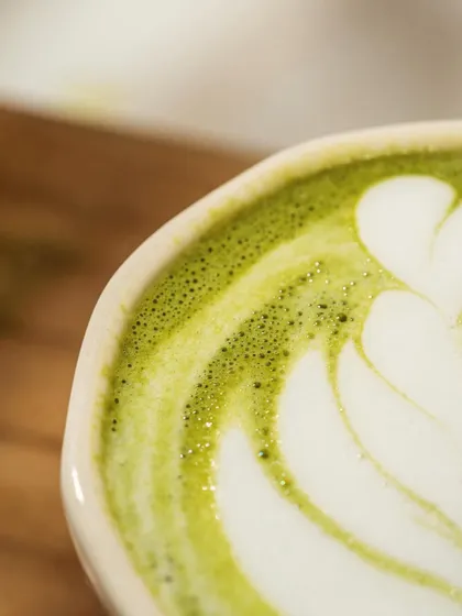 A macro close-up of matcha latte art. This shot focuses entirely on the barista's skill and the creamy texture of the foam, appealing to coffee and tea connoisseurs.