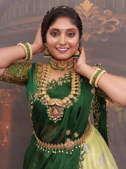 This bride is ready for her photoshoot in a stunning green half-saree. The makeup is bold and beautiful, with a focus on the eyes and a radiant complexion.