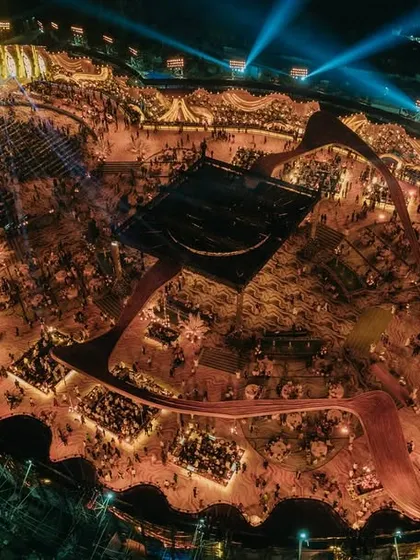 The reception in full swing. This nighttime aerial shot captures the grandeur of the event, with thousands of guests celebrating in a venue transformed into a world of its own.