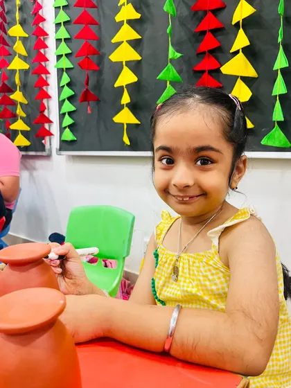 A young artist concentrating on painting her terracotta diya holder for Diwali.