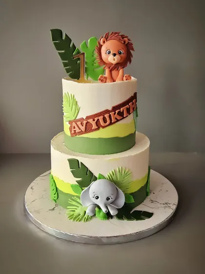 A two-tier jungle cake for Avyukth's first birthday. This 4kg chocolate truffle cake features a fondant lion on top and an elephant at the base, surrounded by jungle leaves.