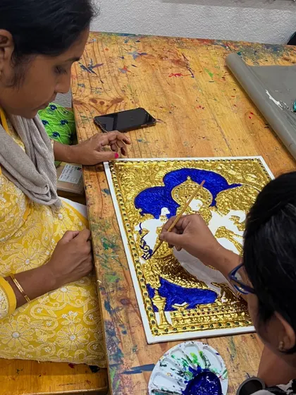 I'm providing guidance to a student on her painting of Radha and Krishna, ensuring her brushstrokes are confident and precise.