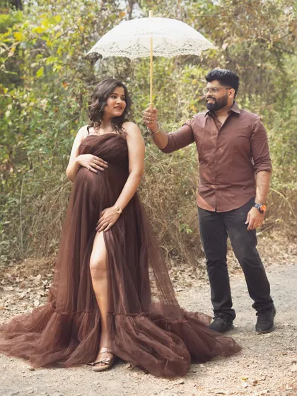 A sweet and playful moment between the couple. The husband-to-be holds the parasol for his wife, creating a charming and protective image during their outdoor shoot.