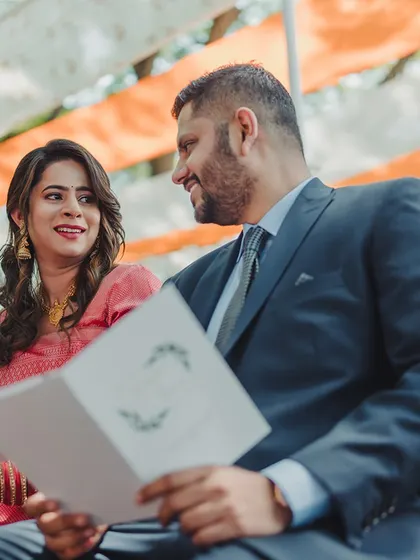 A couple shares a private moment, reading their wedding programs together before the festivities.