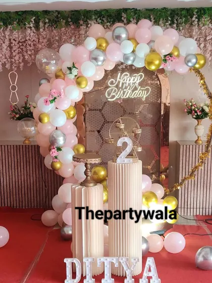 A beautiful ring decoration with a rose gold arch backdrop and pink, white, and gold balloons.