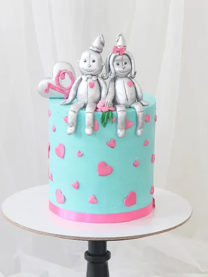 A sweet cake to celebrate a "Tin-versary" or 10th anniversary. This design features adorable, handcrafted tin-man-style figures sitting atop a Tiffany blue cake decorated with pink hearts.