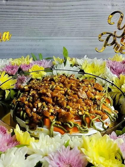 A close-up of the mango pistachio tres leches for Mother's Day, showing the texture of the pistachio praline and the custom "Mom" and "You Are Precious" toppers.