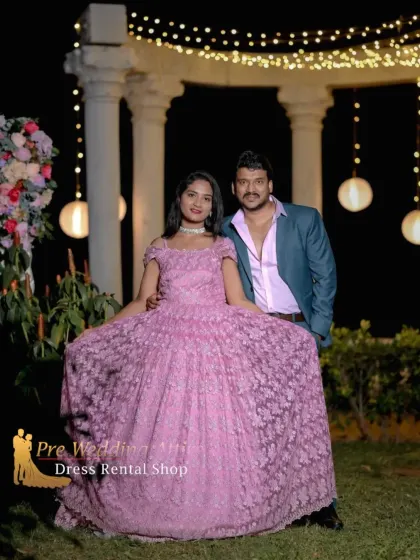 A couple posing at night in a pink lace ball gown and a stylish teal blazer. The combination of the soft pink dress and the bold blazer creates a modern and fashionable look.