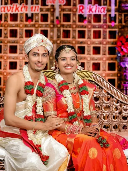 A happy portrait of the bride and groom on their wedding stage, smiling for the camera in their beautiful traditional outfits.