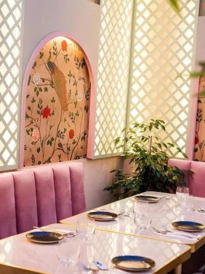 This restaurant's dining nook is elevated with an elegant, custom-fit peacock mural inside an arched alcove. The soft colors and intricate design work with the pink upholstery to create a chic and photogenic dining spot.
